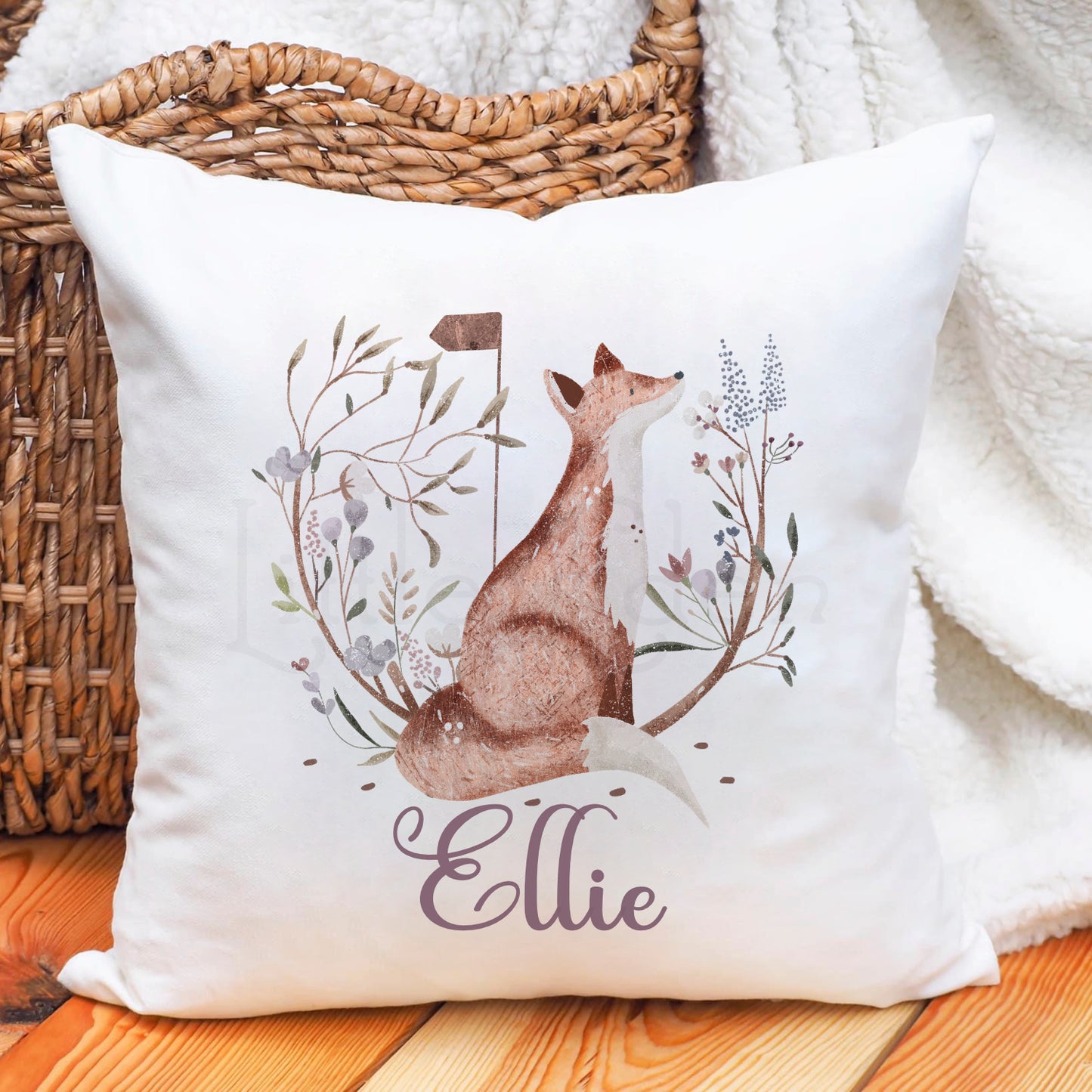 Beautifully illustrated woodland fox personalised cushion. The image shows  fox sitting, surrounded by a wreath of branches and blue, pink and mauve flowers. The Child's name sits underneath the  fox near the bottom of the cushion in a mauve colour. Perfect for a little girls bedroom or nursery, or as a special gift.  A perfect addition to a woodland, nature, floral themed bedroom, play room or nursery