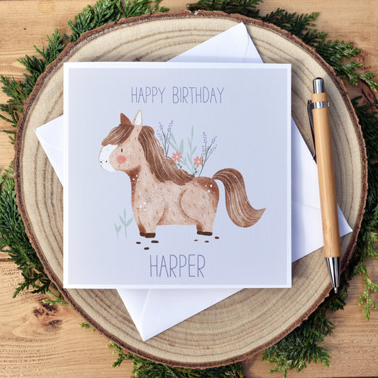 Cute Shetland Pony personalised birthday card. Beautifully illustrated shetland pony on a pale lilac background. Text reads happy birthday with the child's name at the bottom of the card. The card is plain on the inside to write your own message.   